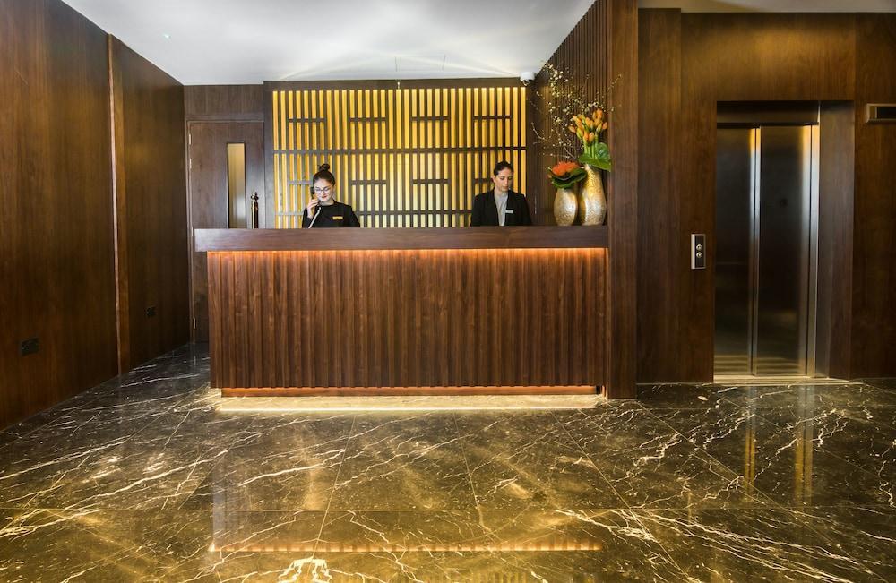 Montcalm Chilworth Townhouse, Paddington Hotell London Eksteriør bilde The photo shows a hotel reception area. At the front desk, two employees are standing behind a wooden counter. The wall behind the counter features a modern design with lines, and there are decorative elements, including a vase with flowers. The floo