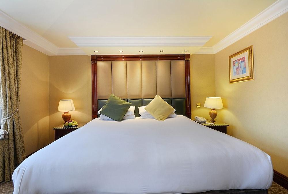 Montcalm Chilworth Townhouse, Paddington Hotell London Eksteriør bilde The photo shows a well-appointed hotel room featuring a large bed with a white blanket. The headboard is upholstered and includes decorative lighting above it. Two decorative pillows in shades of green and yellow are placed on the bed. On either side