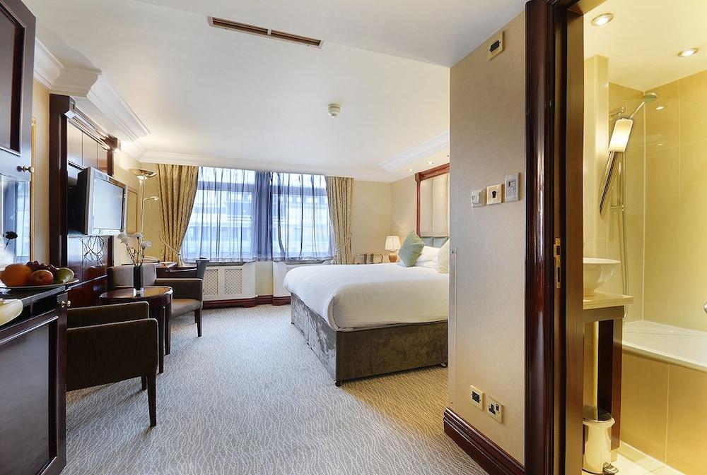 Montcalm Chilworth Townhouse, Paddington Hotell London Eksteriør bilde The photo shows a hotel room that features a spacious layout with a large bed situated in the center. There are two armchairs placed near a small table, contributing to a cozy seating area. A flat-screen television is mounted on the wall opposite the