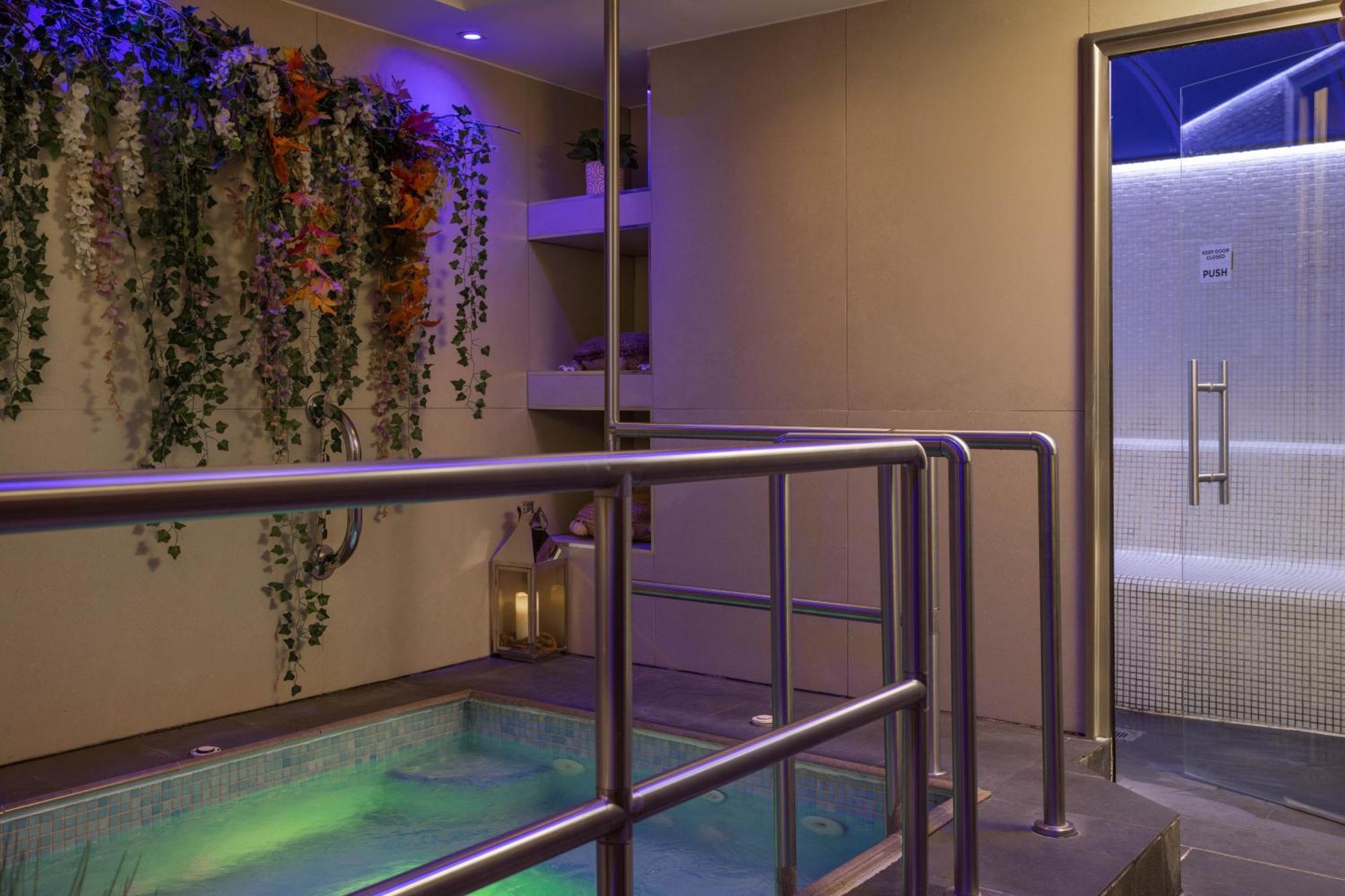 Montcalm Chilworth Townhouse, Paddington Hotell London Eksteriør bilde The photo shows a relaxing spa setting featuring a small jacuzzi or hot tub with illuminated water, creating a tranquil atmosphere. The walls are adorned with decorative plants and flowers, adding a touch of nature. To the side, there is a modern sho