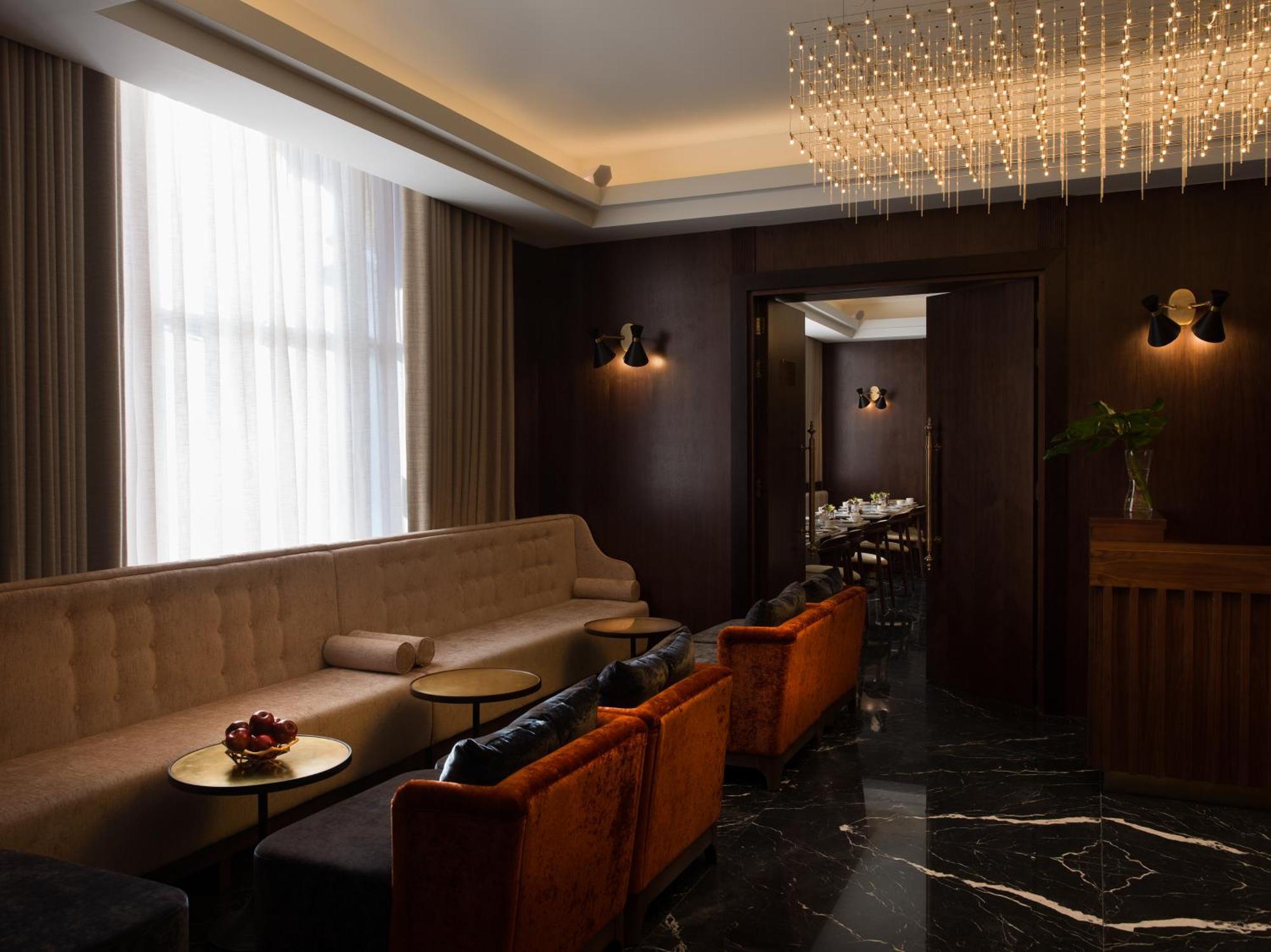 Montcalm Chilworth Townhouse, Paddington Hotell London Eksteriør bilde The photo depicts a modern and elegantly designed lounge area. It features a combination of soft, plush seating with a light-colored sofa and several accent chairs in a rich orange shade. The furniture is arranged around small round tables, suggestin