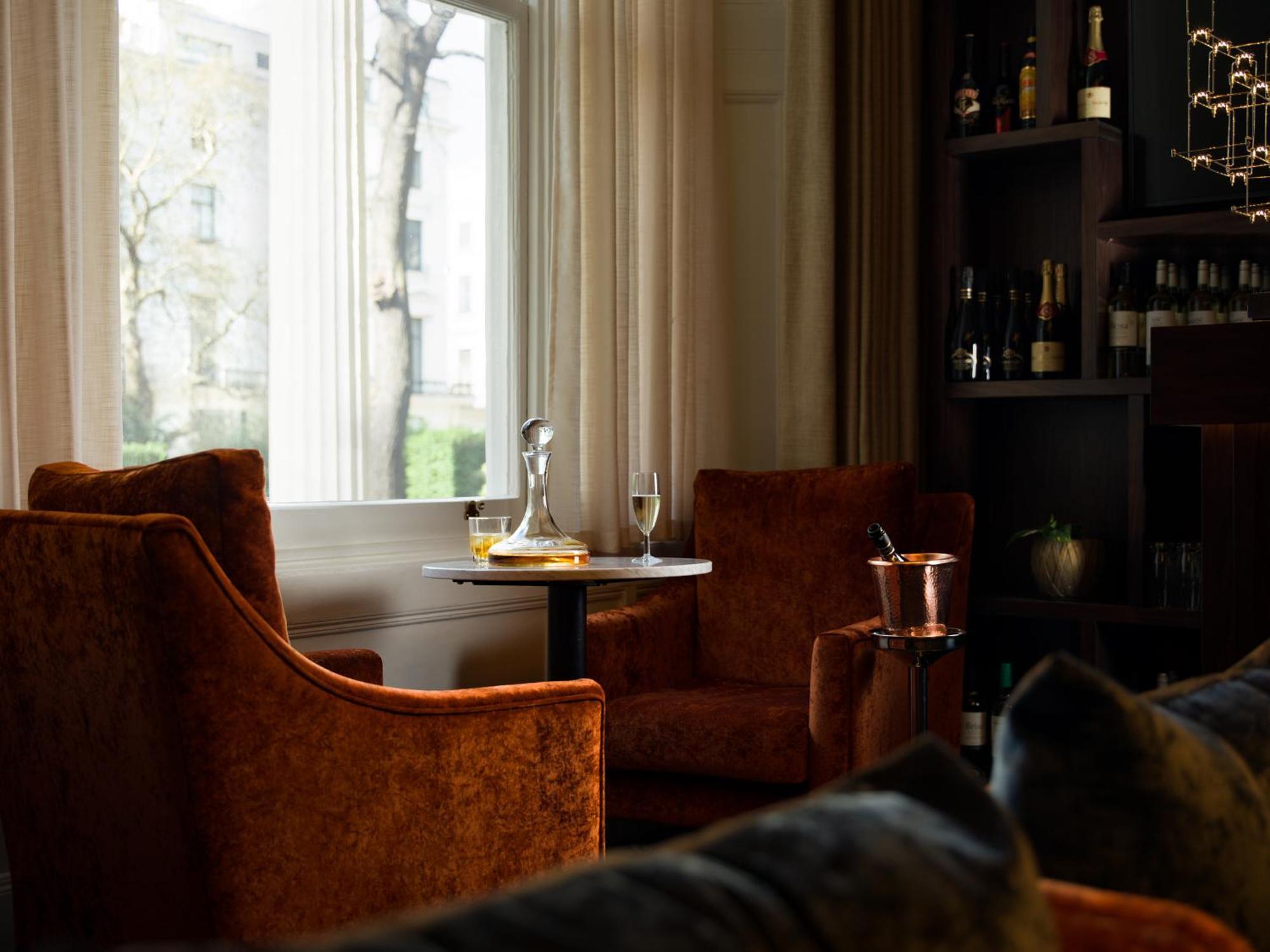 Montcalm Chilworth Townhouse, Paddington Hotell London Eksteriør bilde The photo depicts a cozy interior setting featuring two orange velvet armchairs positioned around a small round table. On the table, there’s a glass decanter and a flute glass, suggesting a setting for drinks. A silver ice bucket is also present. In 