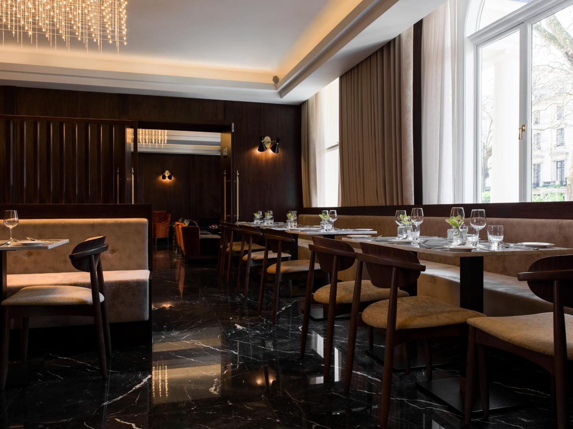 Montcalm Chilworth Townhouse, Paddington Hotell London Eksteriør bilde The photo shows an elegant restaurant interior. The decor features a combination of dark wood and plush seating, creating a refined atmosphere. The floor is made of glossy black marble, reflecting the ambient lighting. Dining tables are arranged neat