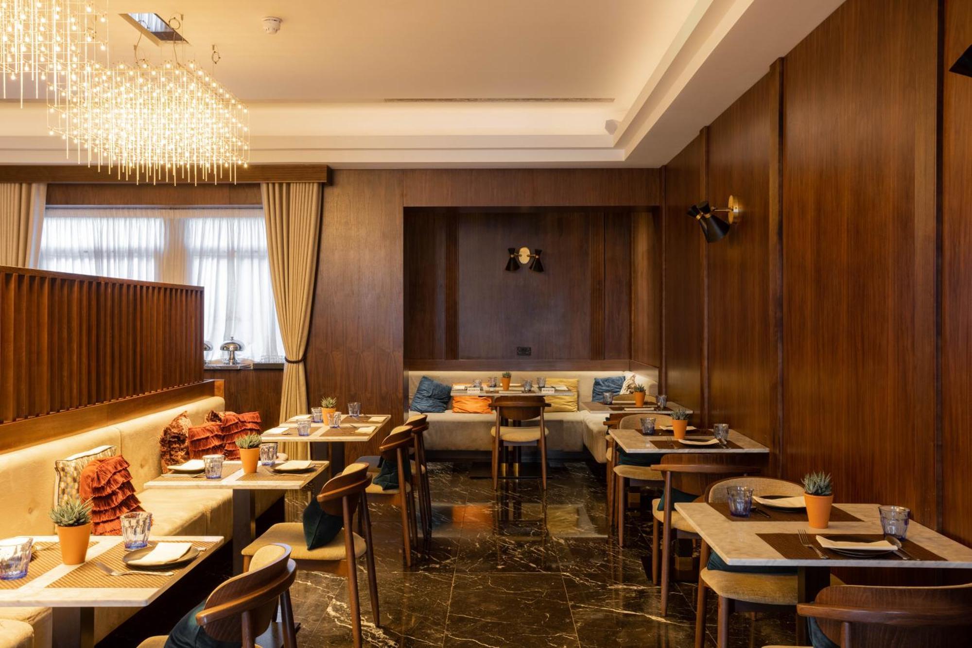 Montcalm Chilworth Townhouse, Paddington Hotell London Eksteriør bilde The photo shows the interior of a restaurant. The design features a warm, inviting atmosphere with wooden paneling on the walls and elegant furnishings. There are several tables set with place settings and small plants as centerpieces. The lighting i