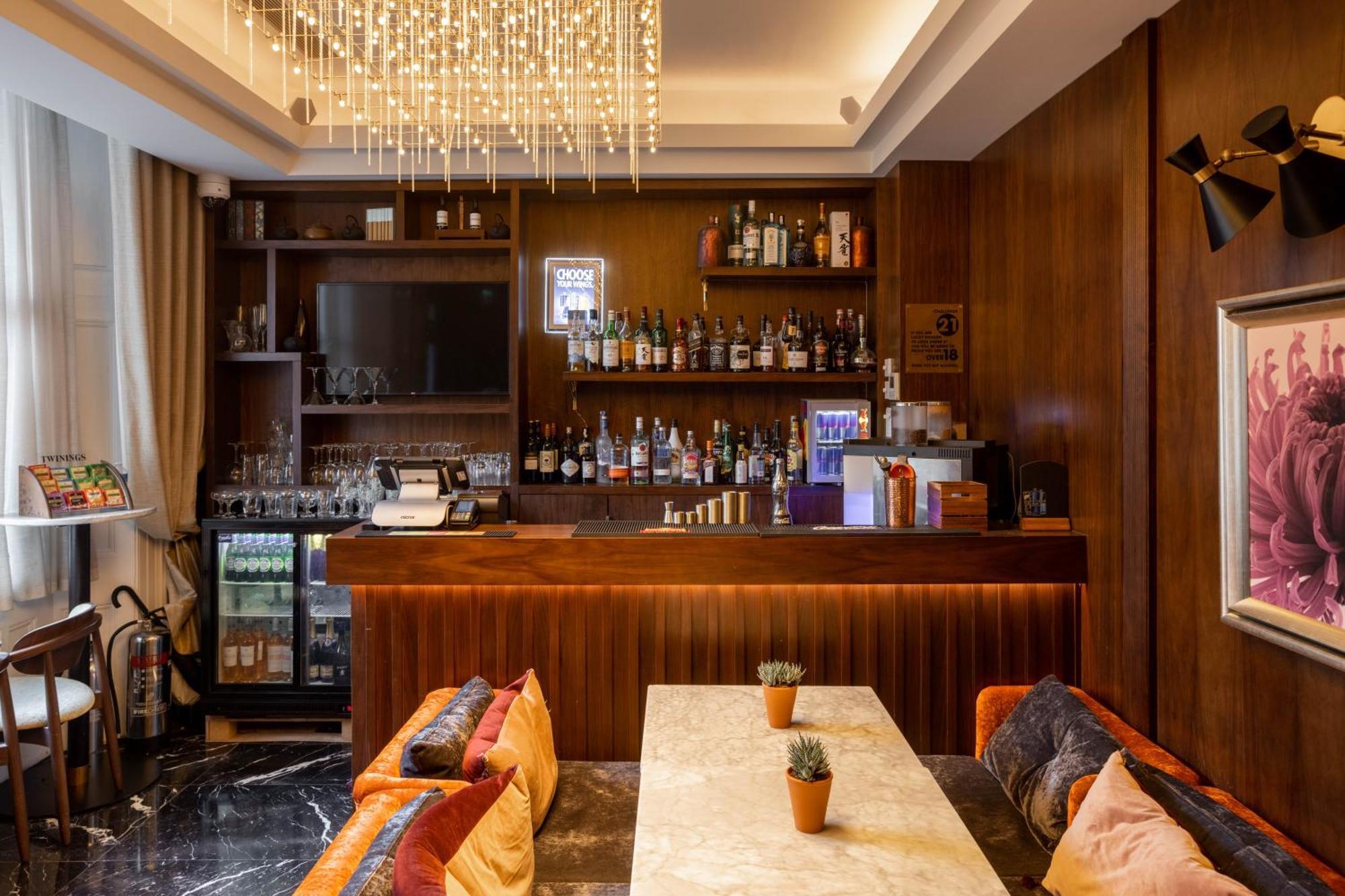 Montcalm Chilworth Townhouse, Paddington Hotell London Eksteriør bilde The image shows a stylish bar area with a modern and elegant design. The bar counter is made of wood and features a variety of alcoholic beverages displayed on shelves behind it. There is a flat-screen TV mounted on the wall, and the bar is illuminat
