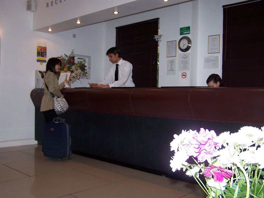 Montcalm Chilworth Townhouse, Paddington Hotell London Eksteriør bilde The photo shows a hotel reception area. There is a front desk behind which a staff member in a white shirt is attending to a guest. The guest, who is holding a bag and has a suitcase beside them, appears to be checking in. The reception area is decor
