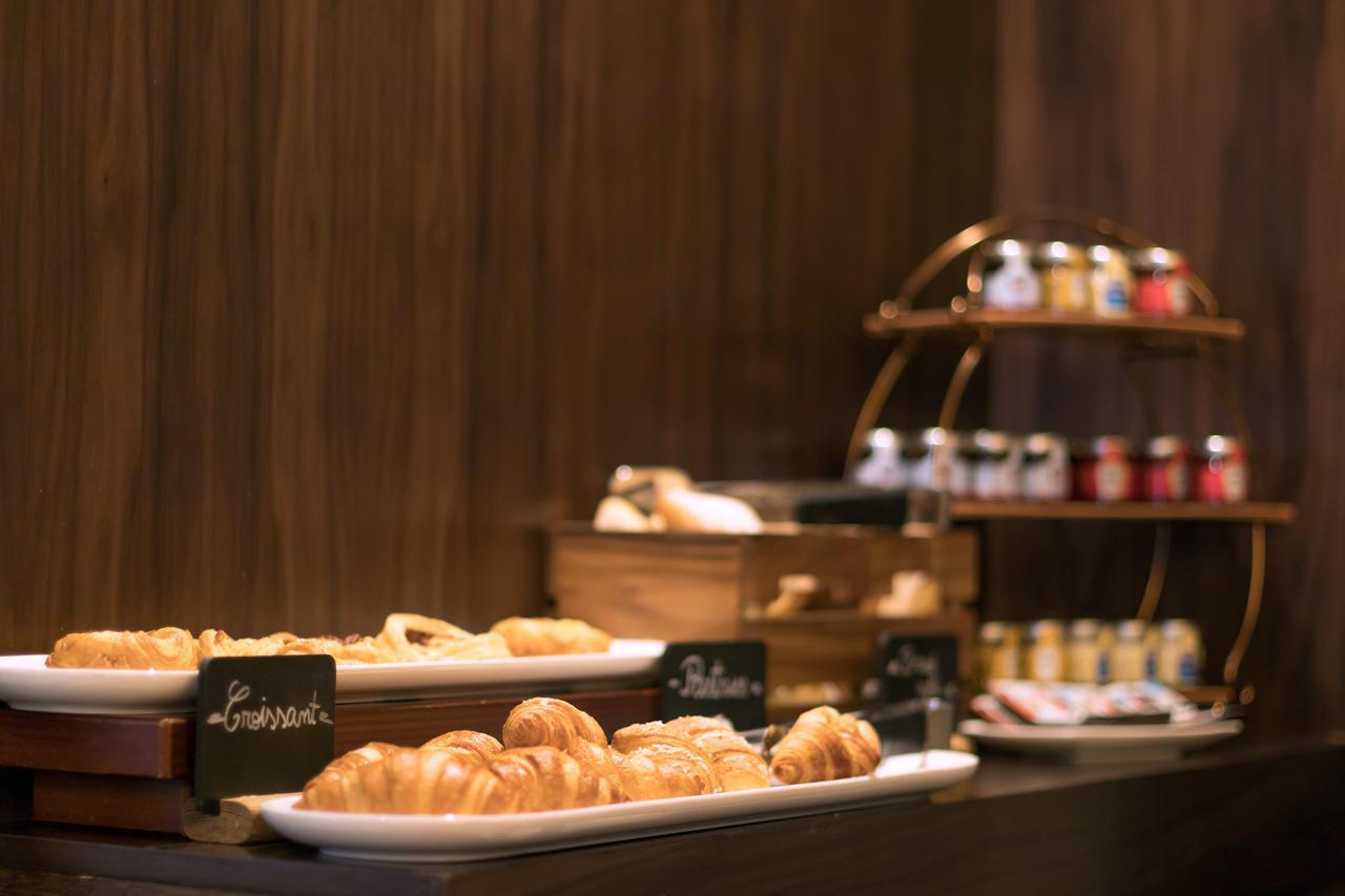 Montcalm Chilworth Townhouse, Paddington Hotell London Eksteriør bilde The photo shows a display of various baked goods and condiments. On the left, there are several trays of pastries, including croissants, placed on a wooden surface. Each pastry is labeled with a small sign, potentially indicating their names or types