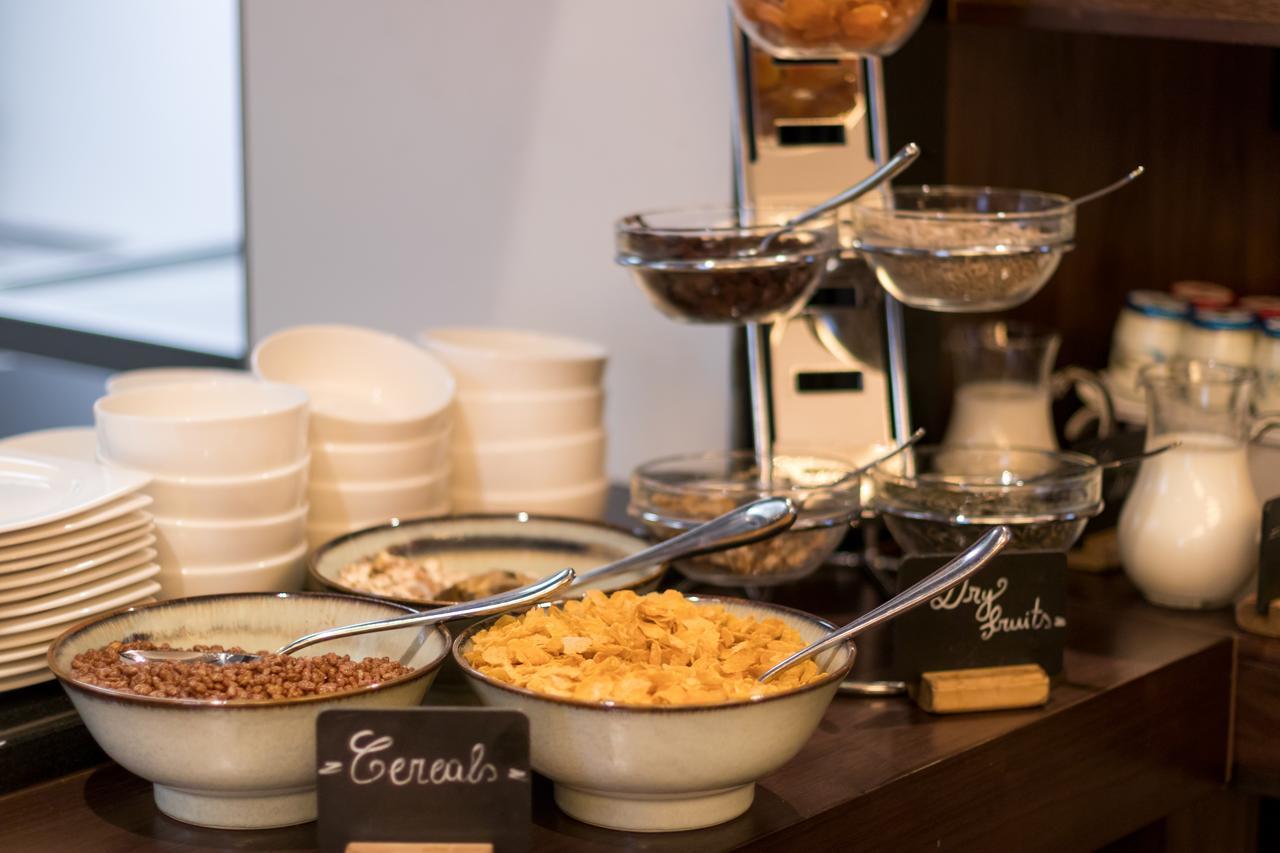 Montcalm Chilworth Townhouse, Paddington Hotell London Eksteriør bilde The photo shows a breakfast buffet setup featuring various cereals. There are multiple bowls containing different types of cereals, such as granola and possibly cornflakes. Each bowl has a spoon for serving. In the background, there are white plates 
