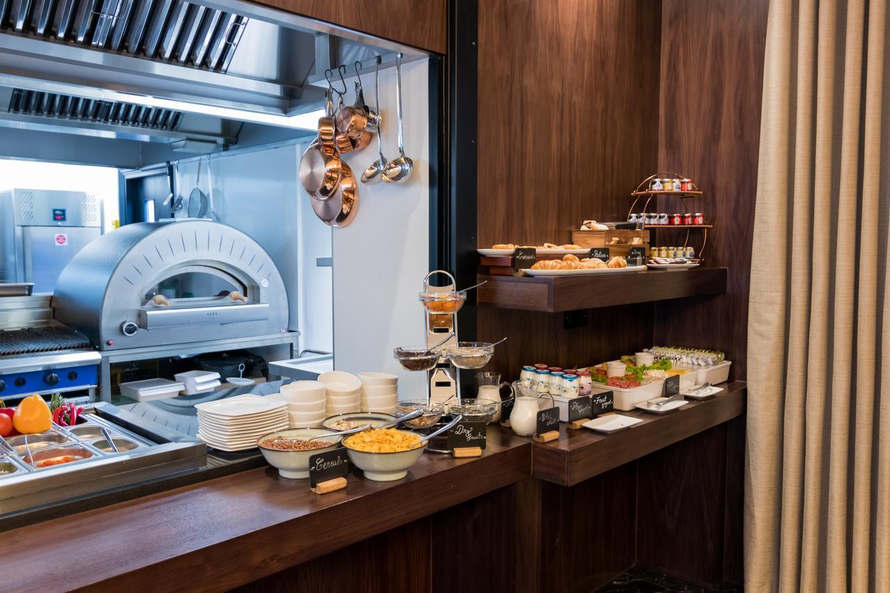 Montcalm Chilworth Townhouse, Paddington Hotell London Eksteriør bilde The photo shows a buffet area in a dining setting. There's a wooden counter displaying a variety of food items. On the left side, there are bowls containing different types of food, possibly salads or sides. On a tiered stand, there are desserts or s