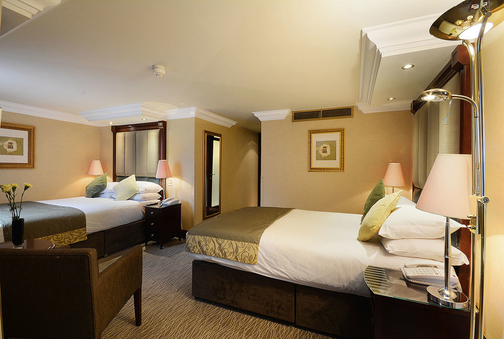 Montcalm Chilworth Townhouse, Paddington Hotell London Eksteriør bilde The photo shows a hotel room featuring two beds with stylish bedding. The room is decorated in warm, neutral tones with beige walls and soft lighting. There are bedside tables with lamps beside each bed, and a comfortable chair positioned in the corn