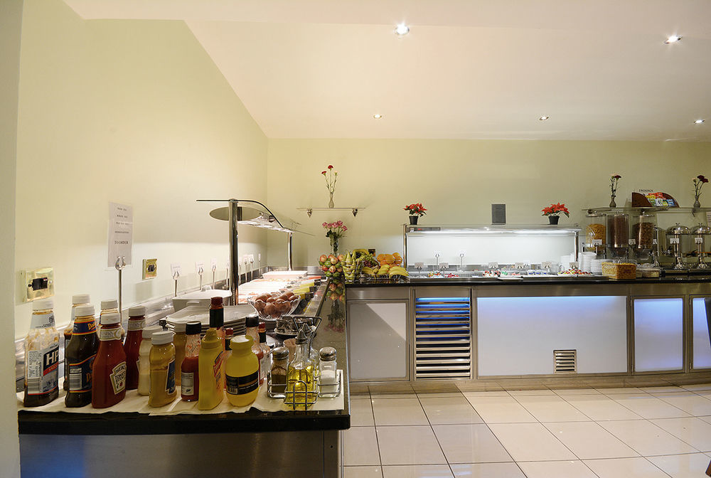Montcalm Chilworth Townhouse, Paddington Hotell London Eksteriør bilde The photo shows a buffet setup in a dining area. On the left side, there are various condiments displayed, including bottles of ketchup, mustard, and oil. To the right, there are sections of food items arranged on a countertop, likely including fruit